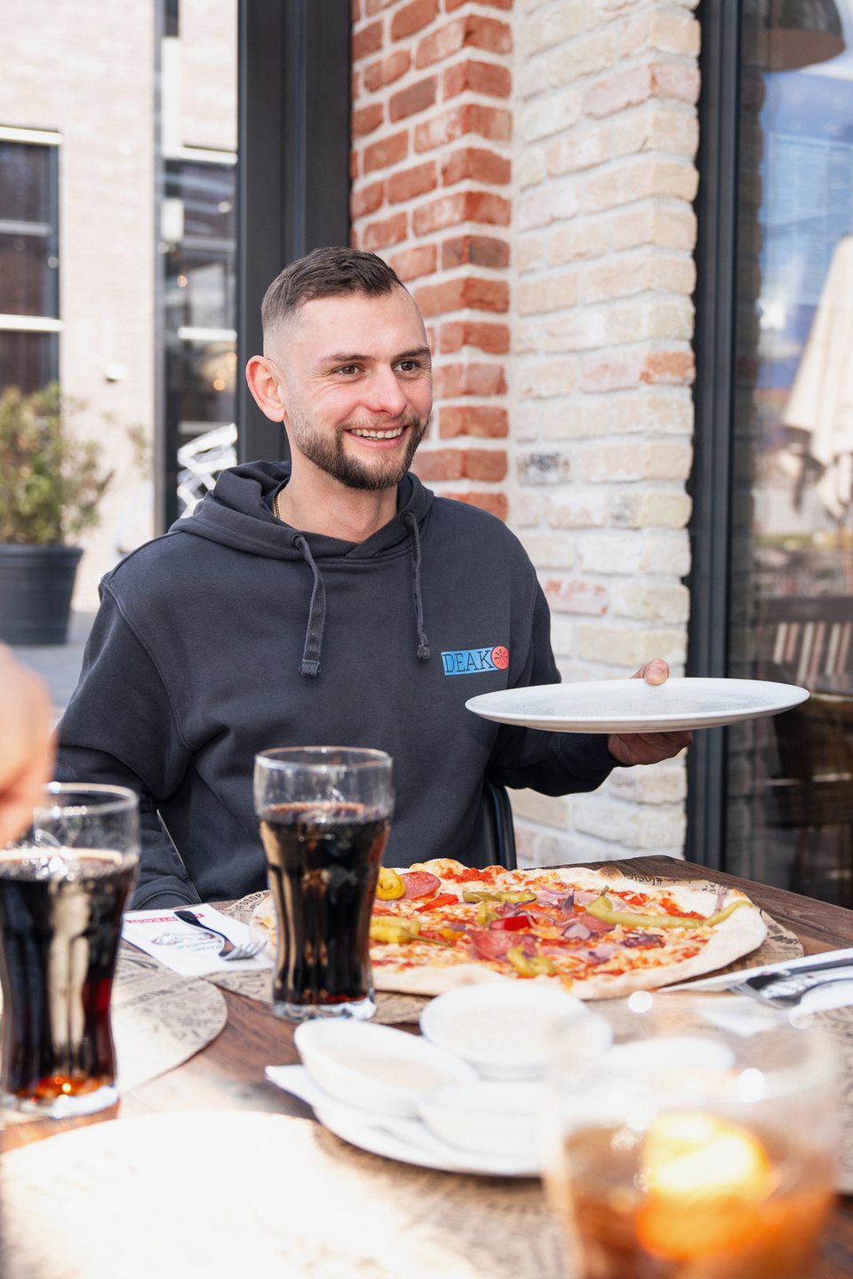 Ein Monteur von Deak bringt beim Feierabendessen die Pizza an den Tisch.